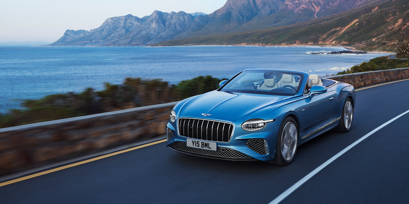 Bentley Stockholm New Bentley Continental GTC Azure convertible in Light Windsor blue paint with 22 inch Azure wheels and chrome grill, driving dynamically by the sea