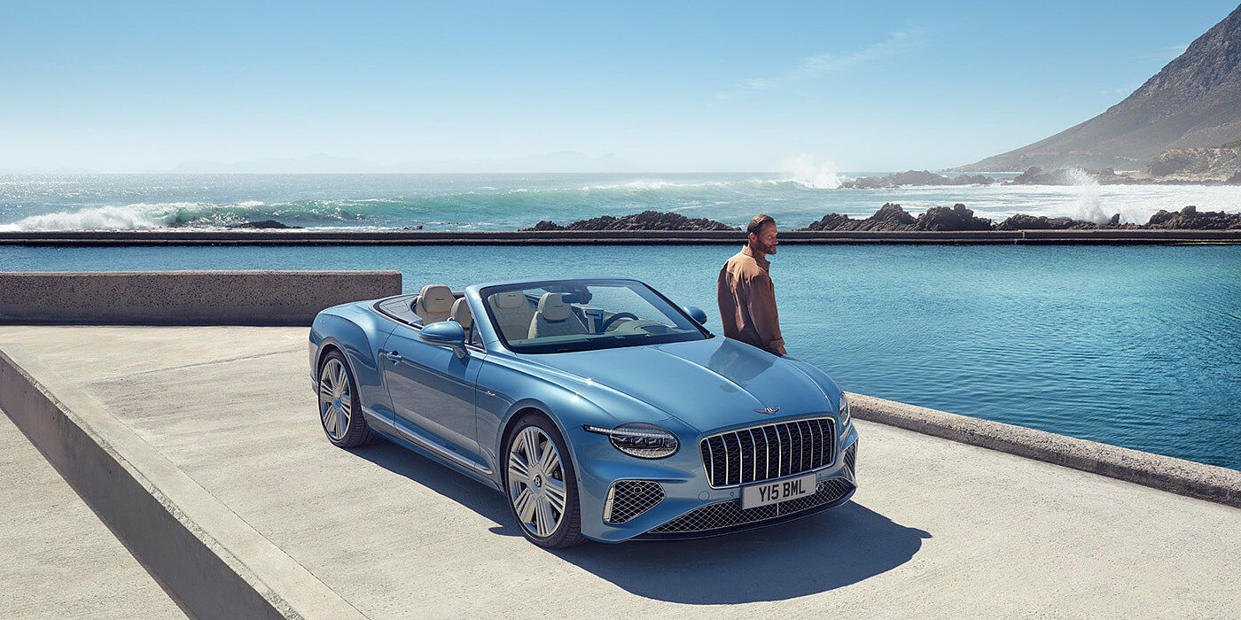 Bentley Stockholm New Bentley Continental GTC Azure convertible front view in Light Windsor blue paint with 22 inch ten spoke wheels parked by the sea in the sunshine