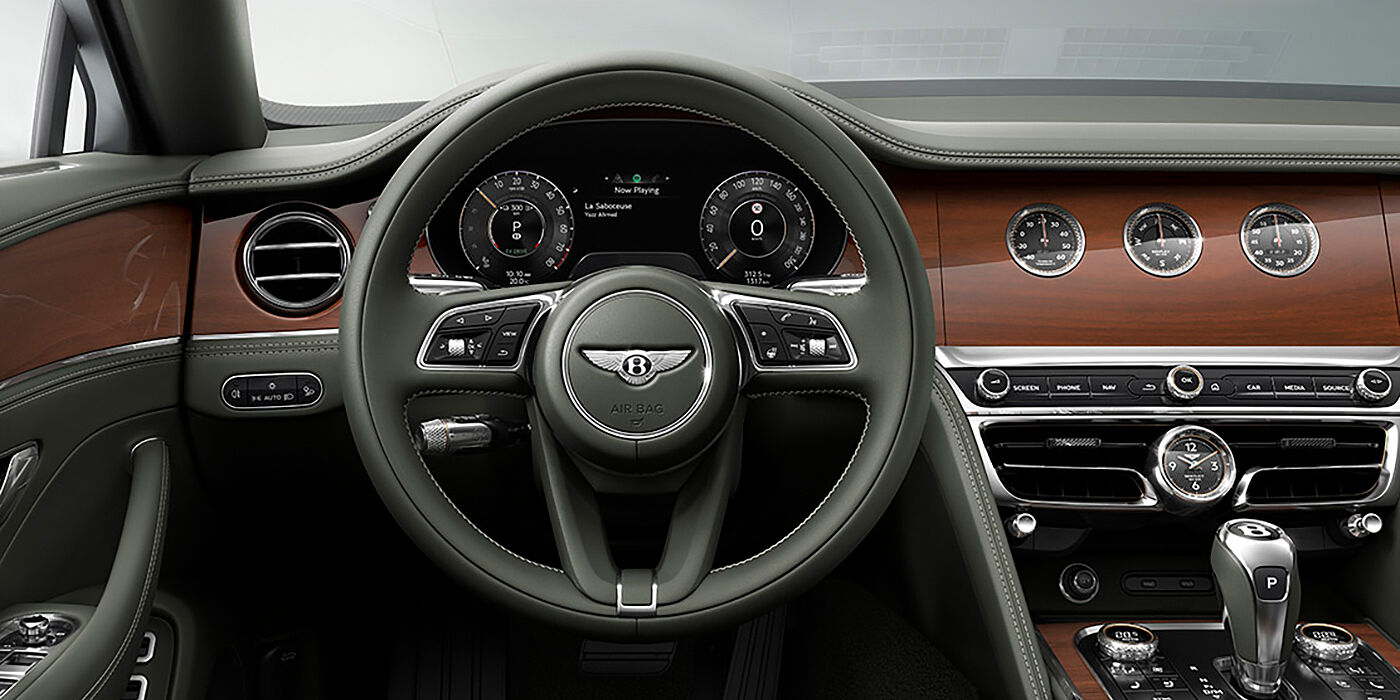 Bentley Stockholm New Bentley Flying Spur sedan front cabin in Cumbrian Green hide and Crown Cut walnut veneer showing steering wheel and Rotating Display with three clocks on face