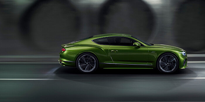  Bentley Stockholm Bentley Continental GT coupe in Tourmaline Green paint driving in profile on a dark road