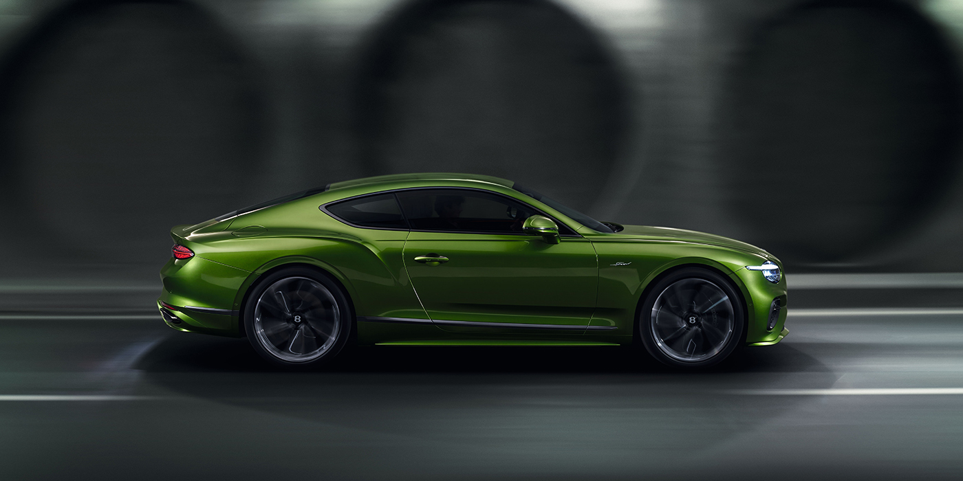Bentley Stockholm Bentley Continental GT coupe in Tourmaline Green paint driving in profile on a dark road